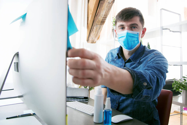 young man in medical mask working with desktop computer at home office - Фото, зображення