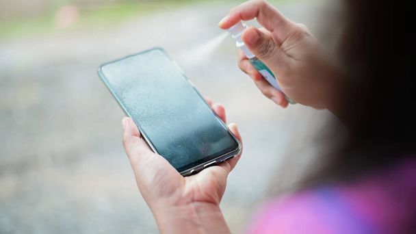 Limpieza de la pantalla del smartphone con aerosol de alcohol y toallitas húmedas de tela para eliminar bacterias y limpieza preventiva de suciedad para la prevención de la contaminación por el brote de Coronavirus COVID-19
. - Foto, Imagen