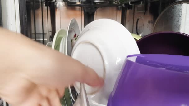 Met behulp van een moderne vaatwasser in het huishouden, nemen de handen van de huisvrouw schone vaat uit de vaatwasser, close-up. Moderne huishoudelijke apparaten thuis. 4K-video. - Video