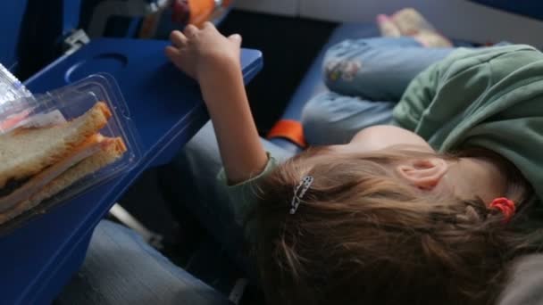 Śpiąca dziewczynka na kolanach matek w samolocie - Materiał filmowy, wideo