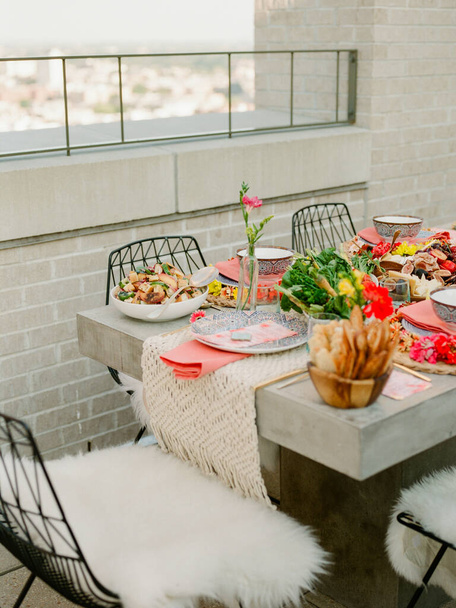 Een kleurrijk ingericht tafellandschap wacht op de gasten voor een diner in de buitenlucht - Foto, afbeelding