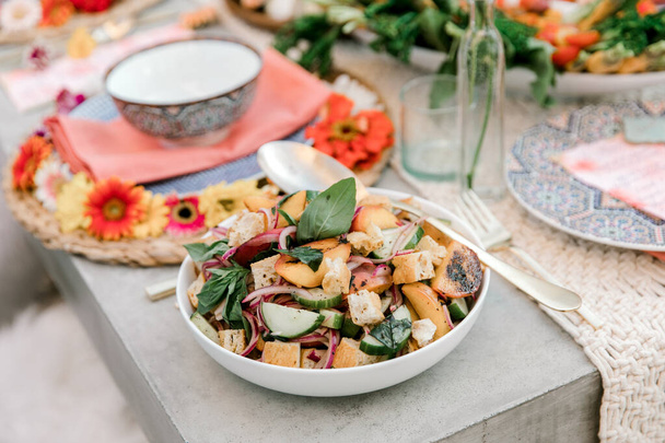 Deliciosas mordeduras de verano de ensalada de verduras con duraznos asados, pepinos, cebollas rojas, albahaca y croutons
, - Foto, imagen