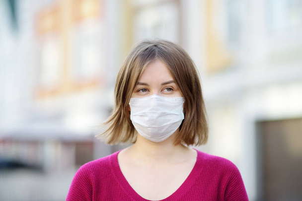 Young woman wearing a protective mask on urban street. Safety during COVID-19 outbreak. Pandemic of coronavirus. - Foto, imagen