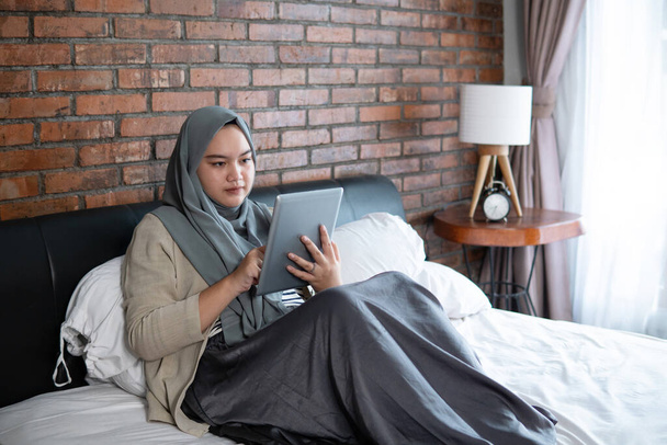 Muslim young woman using tablet looking reservation ticket - Foto, Imagen