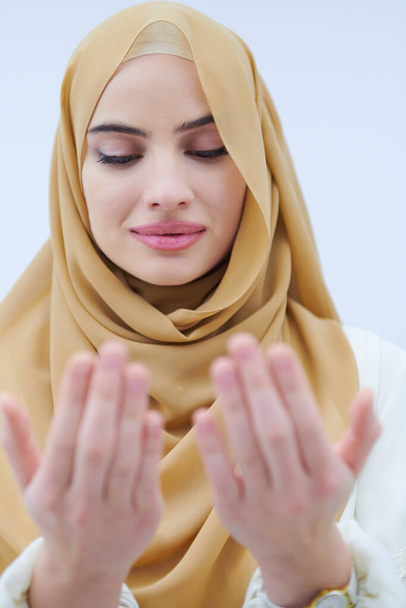 beautiful muslim woman in fashionable dress with hijab making traditional prayer to God, keeps hands in praying gesture isolated on white background representing modern islam fashion and ramadan kareem concept - Zdjęcie, obraz