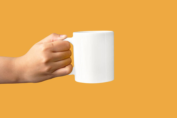 closeup of women hand holding white ceramic a mug mockup isolated on yellow - Фото, зображення
