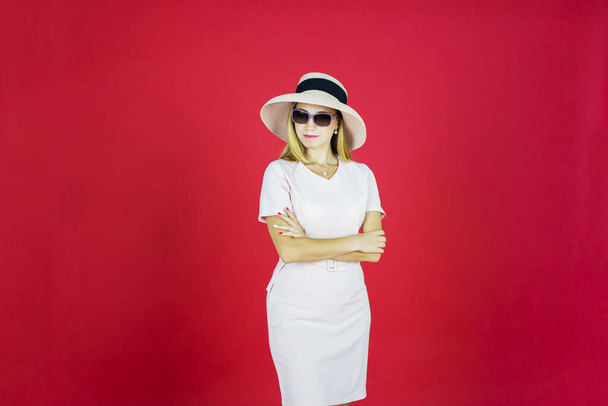 Portrait of attractive woman looks confident while folding her hands with sunglasses, red background  - Foto, Imagen
