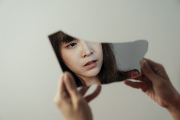 Rikkoutunut peili heijastaa kasvot itsetutkiskeleva thaimaalainen tyttö, koska hän menetti elämänsä tarkoitus
. - Valokuva, kuva