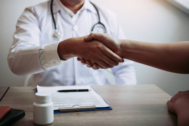 Doctor shaking hands with older patient in the clinic room. - Foto, Bild