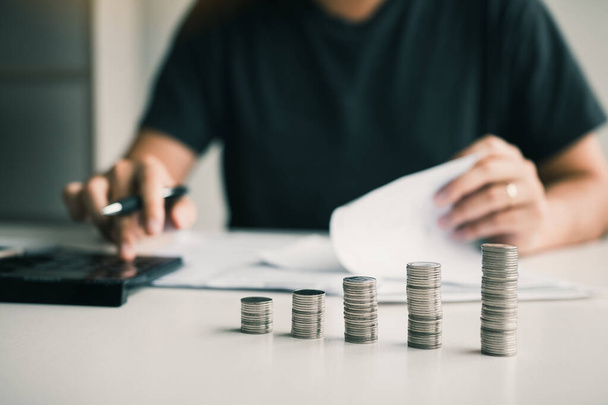 Os homens asiáticos estão calculando sobre as finanças sobre o custo ou o investimento futuro em casa, enquanto as moedas são organizadas com a ideia de salvar
. - Foto, Imagem