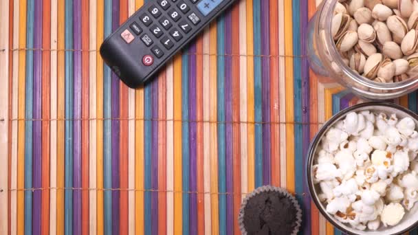 Κοντινό πλάνο των νόστιμων τσιπ, ποπ κορν, παξιμάδι και τηλεχειριστήριο τηλεόραση σε tabne  - Πλάνα, βίντεο