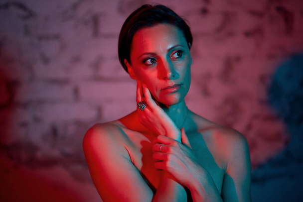 Half-naked woman posing with her hand to her face. The trendy color is red and blue. - Foto, Imagen