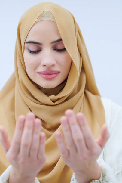 krásná muslimka v módní šaty s hidžáb dělat tradiční modlitbu k Bohu, drží ruce v modlitbě gesto izolované na bílém pozadí představující moderní islám módy a ramadán kareem koncept - Fotografie, Obrázek