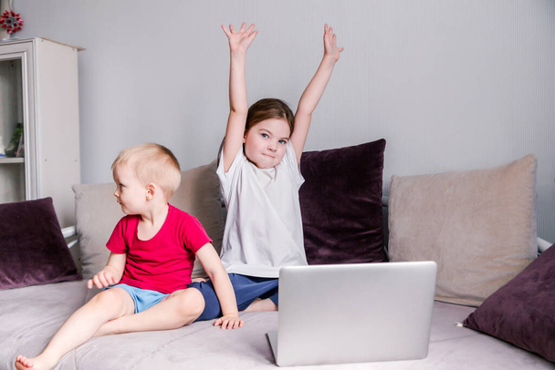 Τα παιδιά στο σπίτι, διασκεδάζοντας, χαζεύοντας, κάνοντας αθλητικές ασκήσεις κοιτάζοντας το laptop. Οριζόντια φωτογραφία - Φωτογραφία, εικόνα