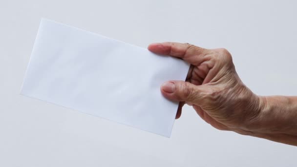 Die rechte Hand der Seniorin mit weißem Umschlag oder Braut auf weißem Hintergrund, Nahaufnahme und Makroaufnahme, Geschäftskonzept - Filmmaterial, Video