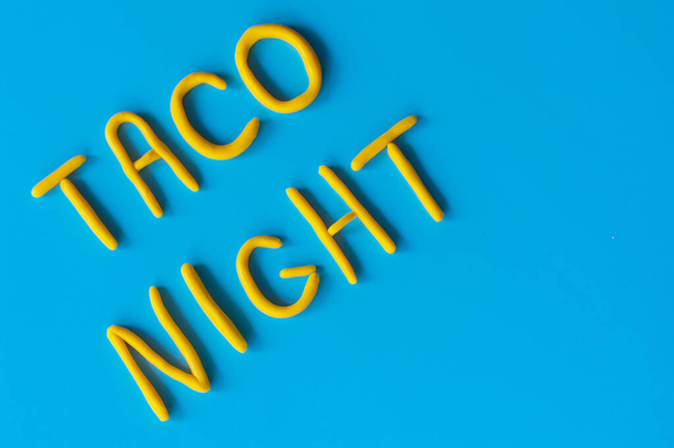 TACO NIGHTという言葉は、青い背景に粘土で作られています。アメリカ、メキシコの休日、テキスト付きの背景. - 写真・画像