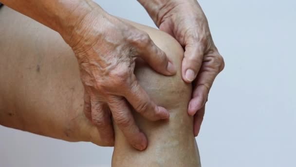Senior woman suffering from left knee pain, Massaging by her hand in white background, Close up & Macro shot, Asian body skin part, Healthcare, About Massage concept - Footage, Video