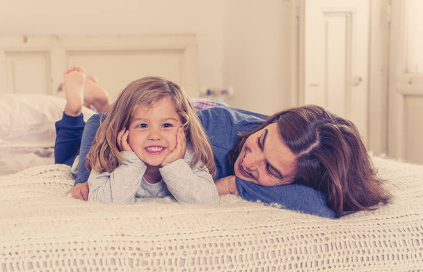 COVID-19 outbreak. Happy single parent woman and little daughter playing together in bed during self isolation. Mother and cute toddler girl in self isolation In Stay at Home campaign concept. - Photo, image