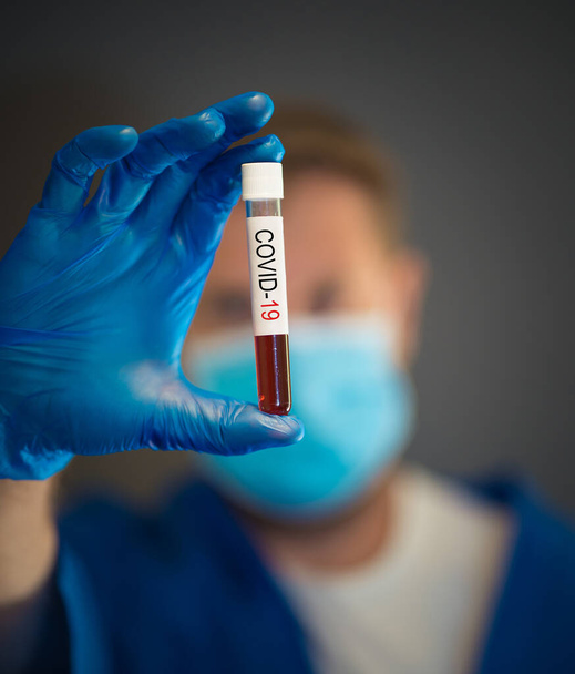 COVID-19. Doctor scientist in Personal Protective Equipment holding vial of blood sample test of infected patient at lab hospital. Coronavirus blood test for medical treatment and vaccine research. - Foto, imagen