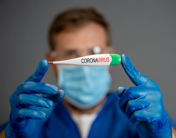 COVID-19 Outbreak. Doctor holding thermometer. Protect yourself and prevent the spread of the coronavirus. If you have symptoms, fever, cough and difficulty breathing, seek medical attention. - Zdjęcie, obraz