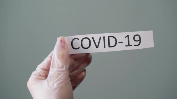 Woman in protective latex gloves holding paper with covid-19 coronavirus text - Záběry, video