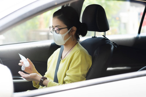 Asian Woman in green or yellow shirt wear protective mask using hand sanitizer gel on her palms for prevent coronavirus or Coronavirus before driving a car. Cleaning, Antiseptic, Hygienic, Healthy and Health care - Foto, Bild