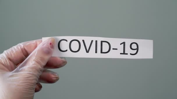 Woman in protective latex gloves holding paper with covid-19 coronavirus text - Кадры, видео