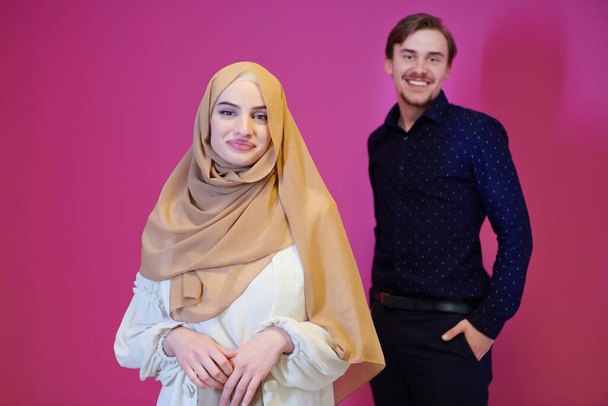 portrait of young muslim couple woman in fashionable dress with hijab isolated on pink background representing modern islam fashion and ramadan kareem concept - Fotografie, Obrázek