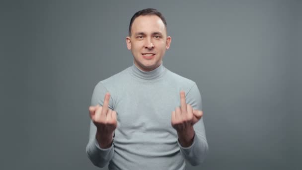 Boğazlı kazaklı genç adamın orta parmaklarını gösteren videosu. - Video, Çekim