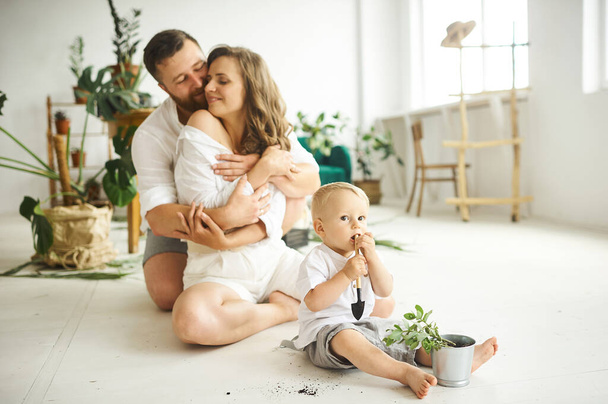 Happy family working at home. Transplanting plants with their child - 写真・画像