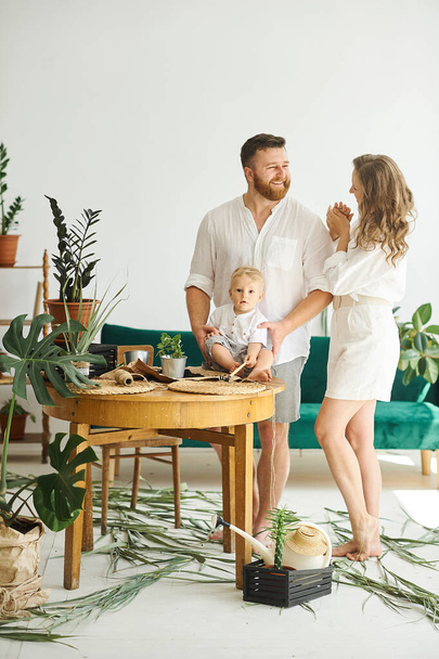 Happy family working at home. Transplanting plants with their child - Foto, imagen