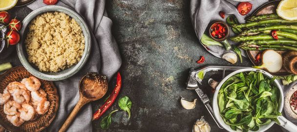 Terveellinen salaatti valmistelu ruoanlaitto-lusikalla ja superelintarvikkeiden ainesosilla: kvinoa, parsa, tuoreet meret, mausteet ja katkaravut maalaismaisemalla, ylhäältä, rajalla
 - Valokuva, kuva
