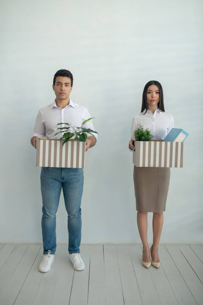 Man and woman standing next close to each other holding boxes - Foto, imagen
