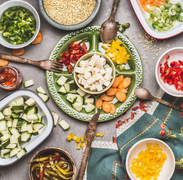 Egészséges vegetáriánus salátakészítés kockázott feta sajttal, vágott zöldségekkel és gyöngyárpával, felülnézetből. Táplálkozás - Fotó, kép