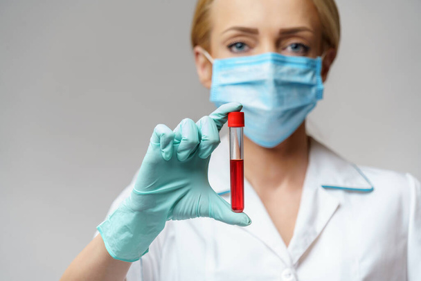 medical doctor nurse woman wearing protective mask and gloves - holding virus blood test - Фото, зображення