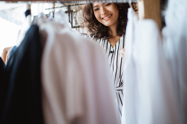 kobieta patrząc na niektóre ubrania w sklepie mody - Zdjęcie, obraz