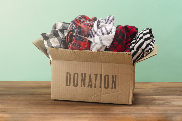 Bağış konsepti. Ahşap bir arka planda bağış giysileri olan bağış kutusu. Hayırseverlik. İhtiyacı olanlara yardım - Fotoğraf, Görsel