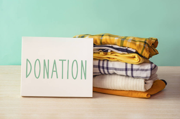Bağış konsepti. Ahşap bir arka planda bağış giysileri olan bağış kutusu. Hayırseverlik. İhtiyacı olanlara yardım - Fotoğraf, Görsel
