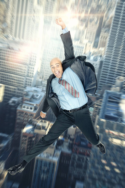 Uomo d'affari che salta in alto con grandi edifici come sfondo
 - Foto, immagini