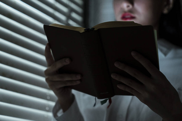 Image recadrée d'un livre dans la main d'une femme pendant qu'elle le lisait à la fenêtre
. - Photo, image