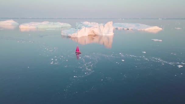 Egy kis csónak között jéghegyek. Vitorlás hajózás között úszó jéghegyek a Disko Bay gleccser alatt éjfél v Ilulissat, Grönland. A globális felmelegedés jelenségének tanulmányozása ICES és jéghegyek - Felvétel, videó