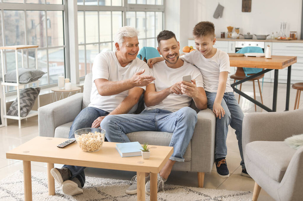 Man with his father and son using mobile phone at home - Foto, Bild