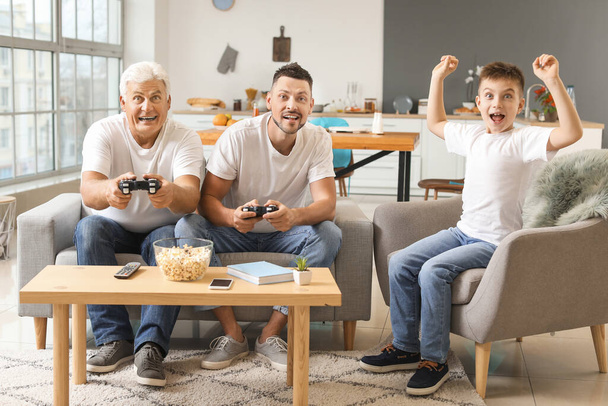 Hombre con su padre e hijo jugando videojuegos en casa
 - Foto, Imagen