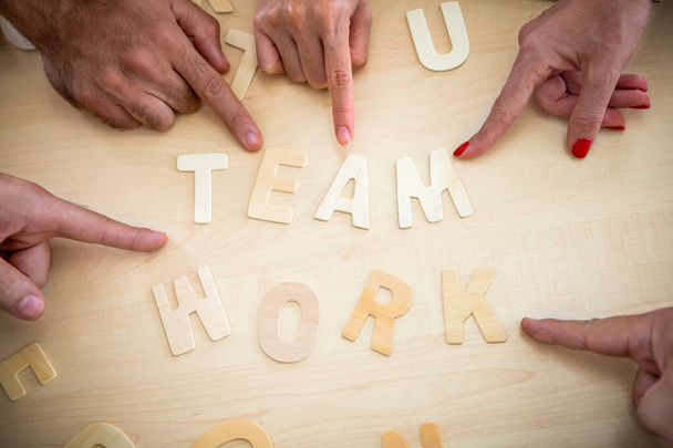 木製の背景にチームワークの木の単語を指して手と指のグループ。団結と協力の概念 - 写真・画像