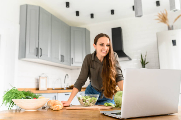Nainen katsomassa ruoanlaitto video keittiössä
 - Valokuva, kuva