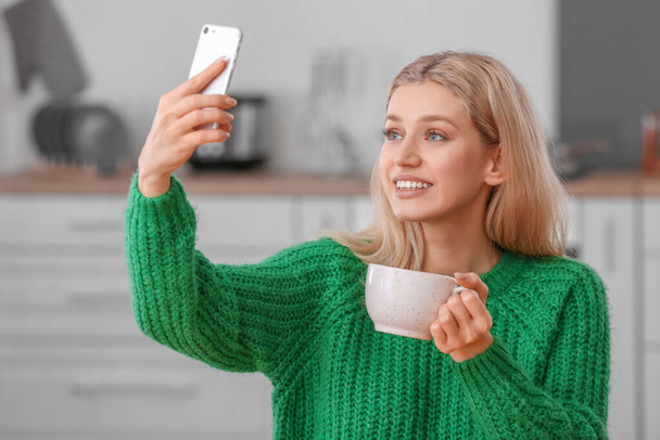 Krásná mladá žena se selfie při pití čaje doma - Fotografie, Obrázek