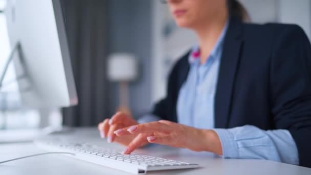 Silmälasipäinen nainen näppäilemässä tietokoneen näppäimistöä. Etätyön käsite. - Materiaali, video