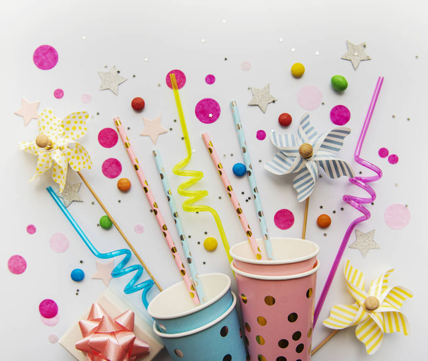 Chapeaux de fête d'anniversaire, pailles de papier, bonbons et confettis sur fond blanc - Photo, image
