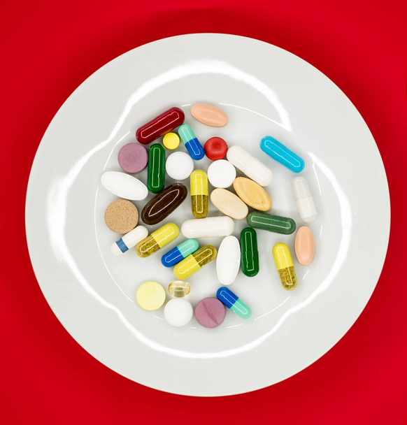 fehér lemez gyógyszerészeti tabletták piros háttér - Fotó, kép