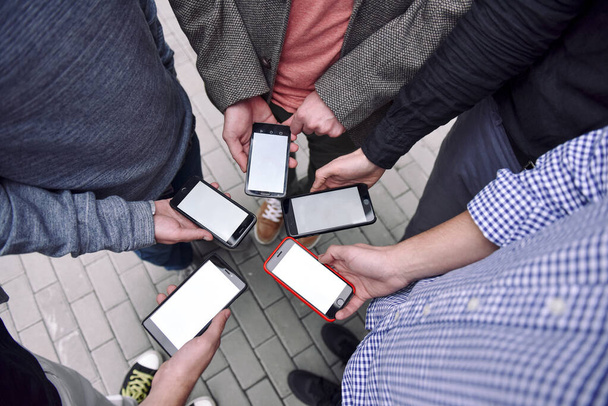 Close-up image of young men group hands  using smartphone on the sreet city - Fotó, kép